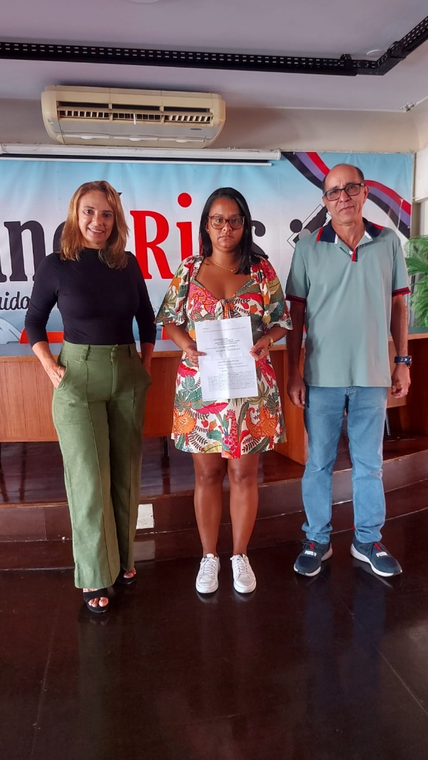 Michele segura a ordem de reintegração, tendo a seu lado a diretora da Secretaria de Assuntos Jurídicos Adriana Nalesso e o diretor Wanderlei Souza