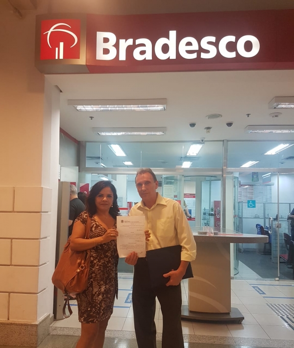 O bancário César Ricardo da Silva de posse de seu documento de reintegração, ao lado da diretora do Sindicato, Sandra Torres