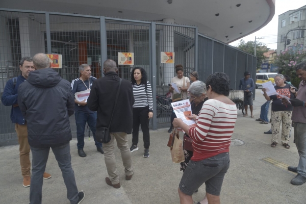 Populares lêem o panfleto e a edição do Jornal Bancário durante o protesto do Sindicato do Rio, em Bonsucesso, contra as demissões no Itaú 